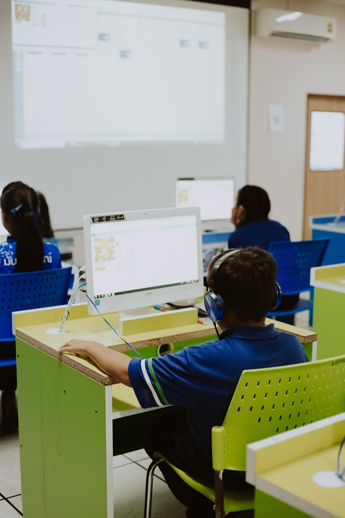 Children engaged in learning at a computer lab, using computers in a classroom setting.